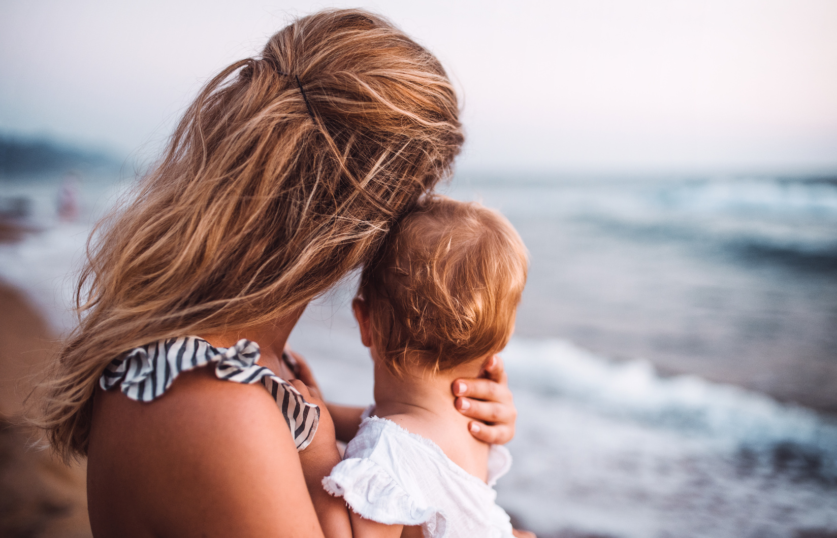 Rear View of Young Mother with a Toddler Girl on Beach on Summer Holiday.